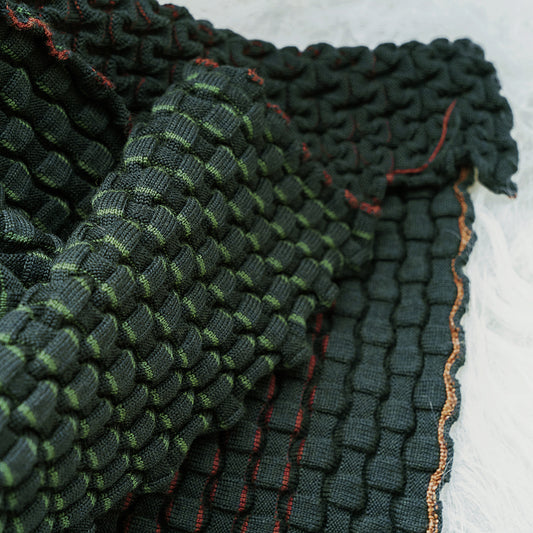 Detail van het groene accordeonreliëf van de CANDY merinowollen plaid