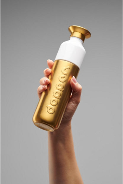 Dopper Steel drinkfles 800 ml Gold, in de hand tegen een grijze achtergrond