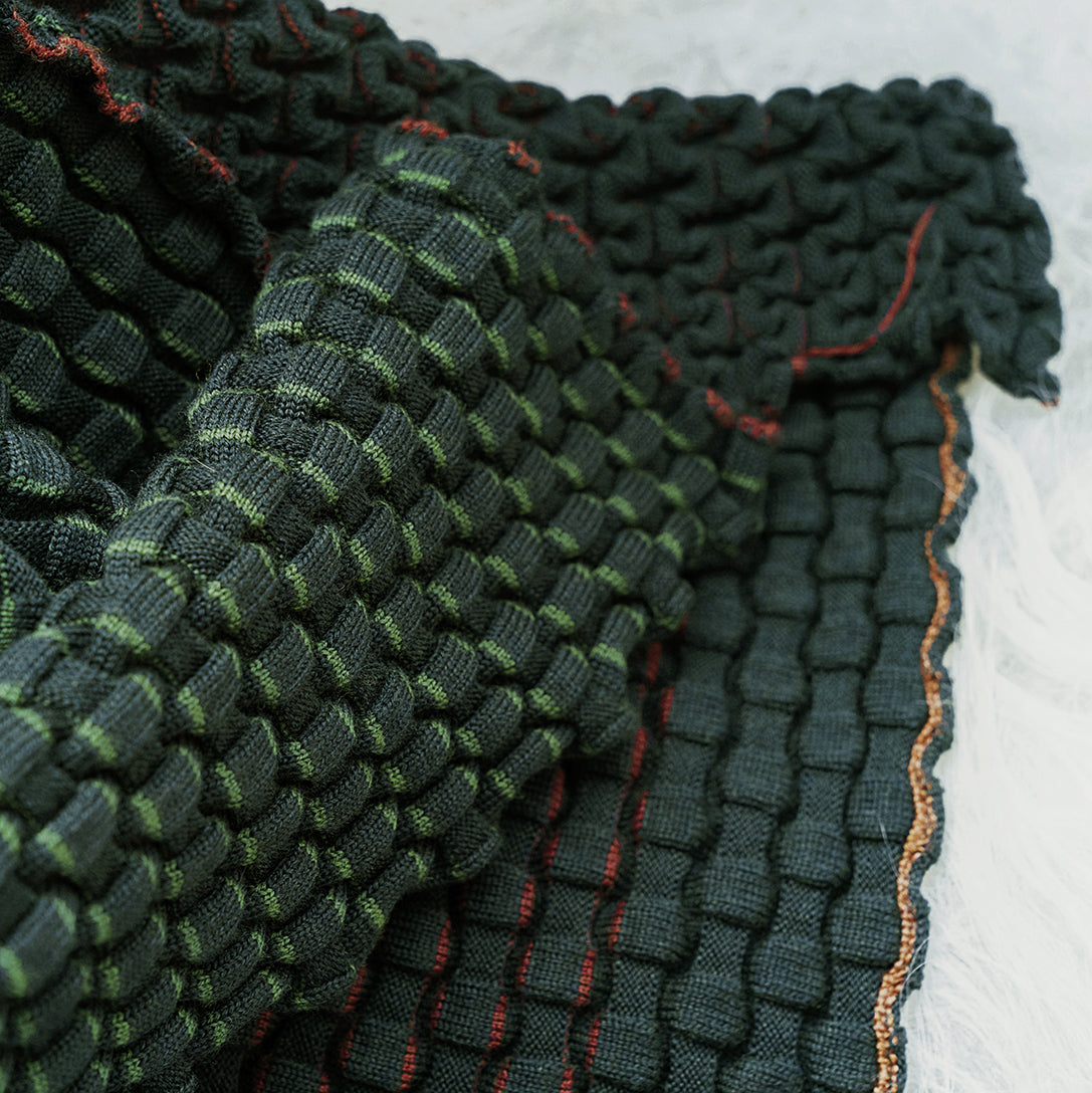 Detail van het groene accordeonreliëf van de CANDY merinowollen plaid