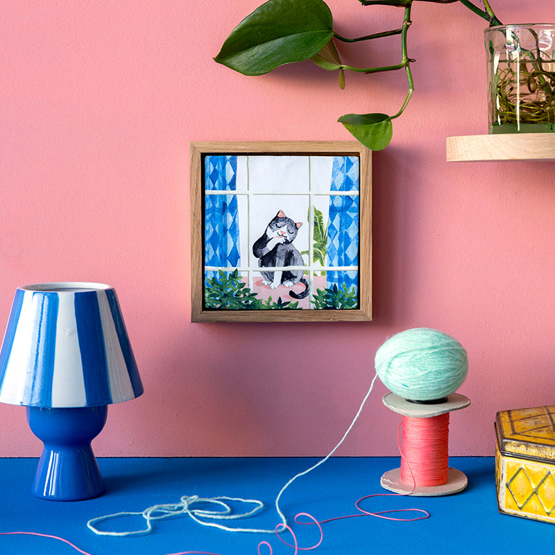 StoryTiles Cosy cat: een kat voor het raam met gordijnen in interieur