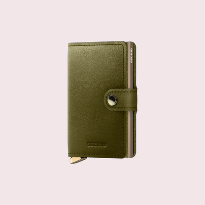 Secrid Premium Miniwallet Dusk Olive tegen een zachte pastelachtergrond (poederroze)