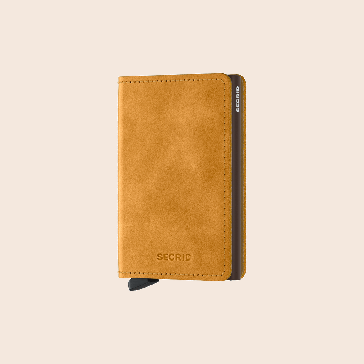 Secrid Slimwallet Vintage Ochre tegen een zachte pastelachtergrond (perzik)