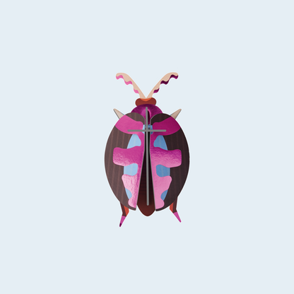 Studio ROOF Lumen Pink Beetle tegen een zachte pastelachtergrond (lichtblauw)